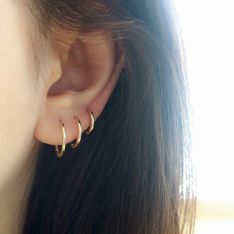 gold slim hoop earrings in solid 14k gold featuring stacked triple lobe piercings