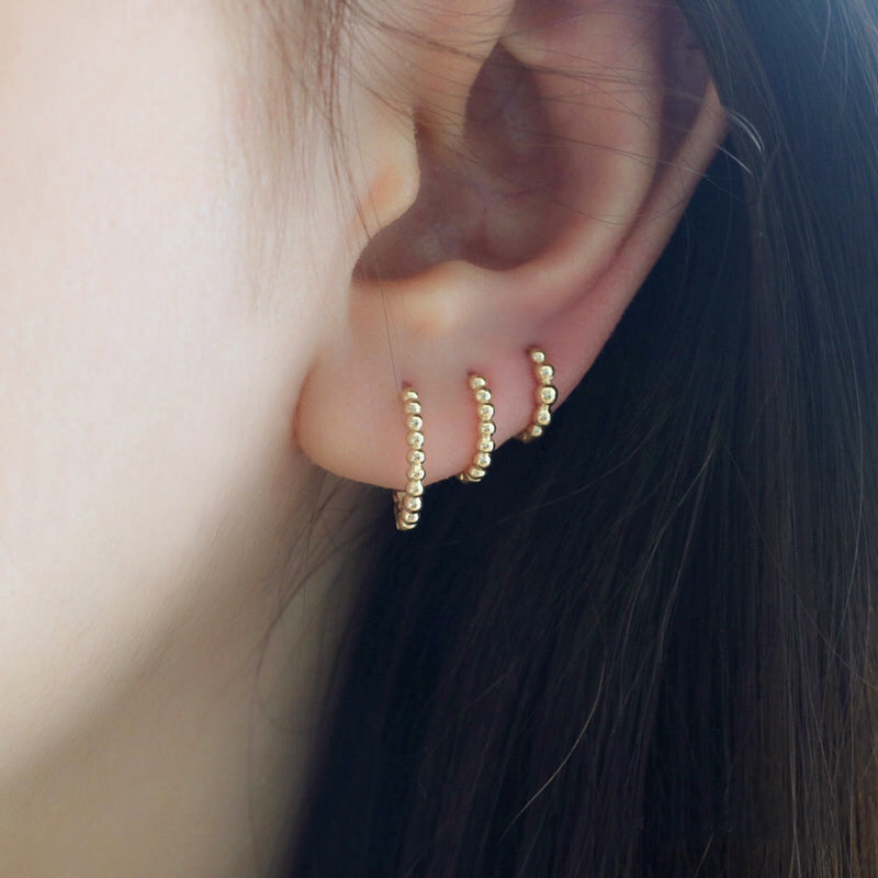 stacked triple ear lobe piercings featuring 14k gold huggie hoops