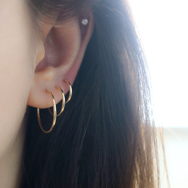 gold hoop earrings in triple ear lobe stacked piercings